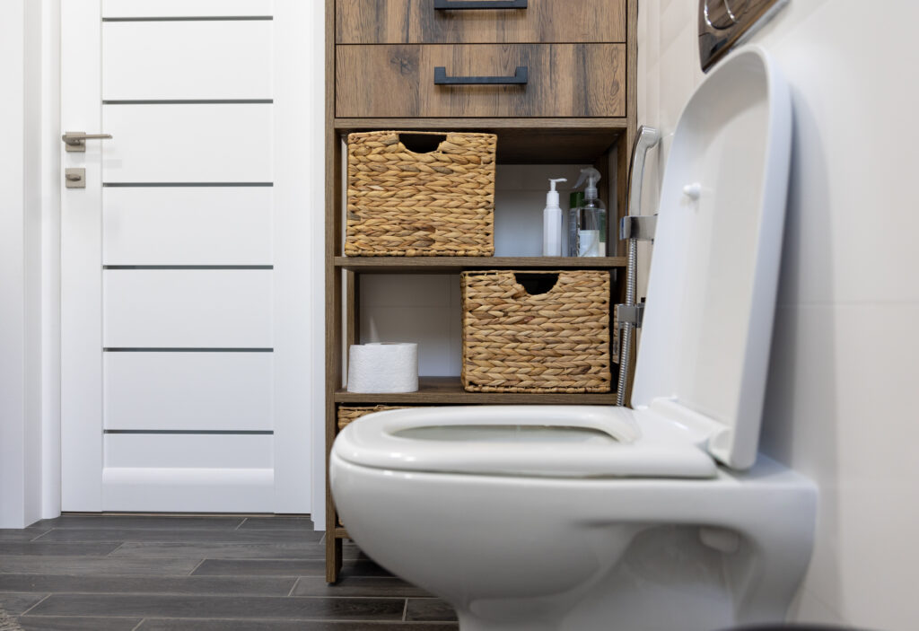 Siège de toilettes dans une salle de bain avec de la décoration et des rangements en fond